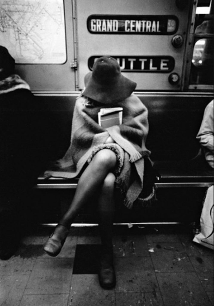 Une jeune fille, un chapeau sur la tête, un livre à la main. Dans le métro